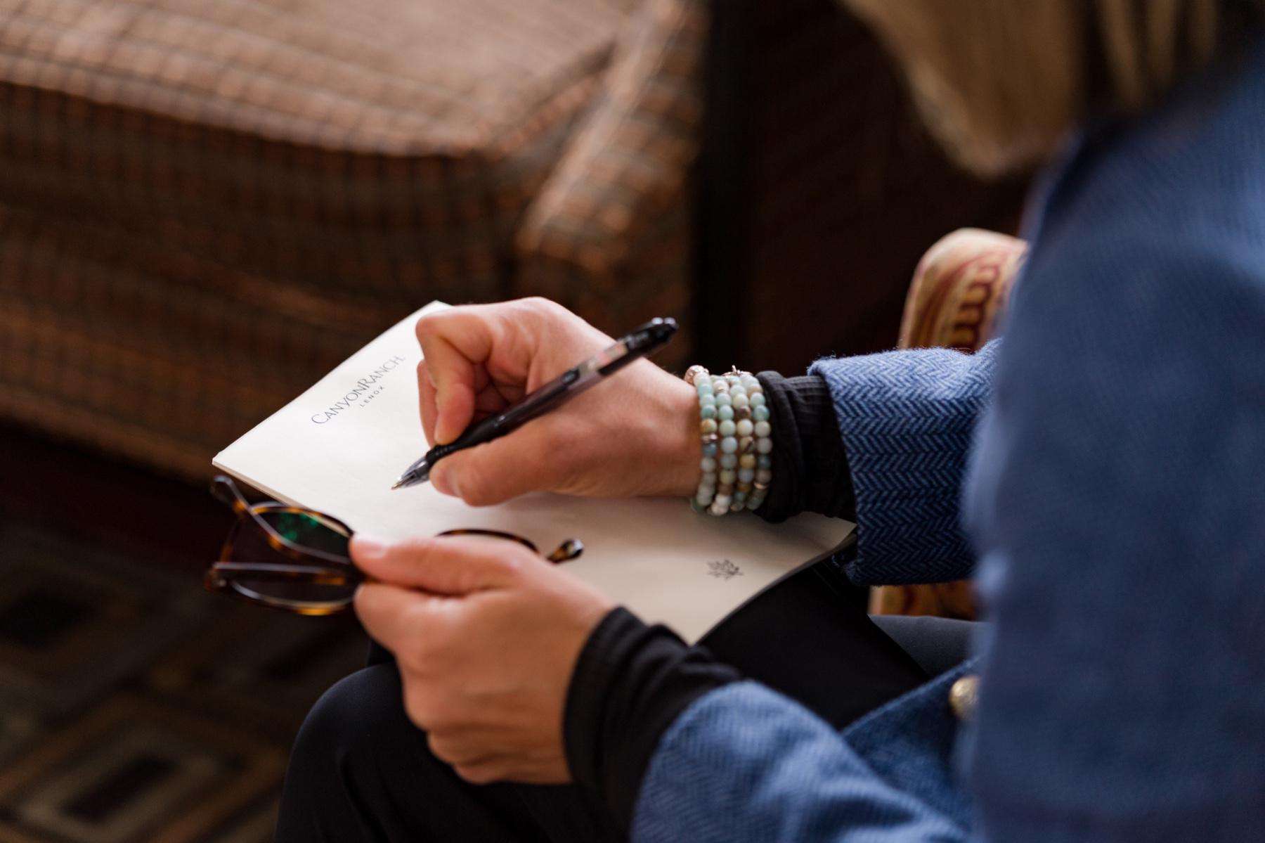 Close-up of woman's hand as she writes with a pen on a pad of paper.