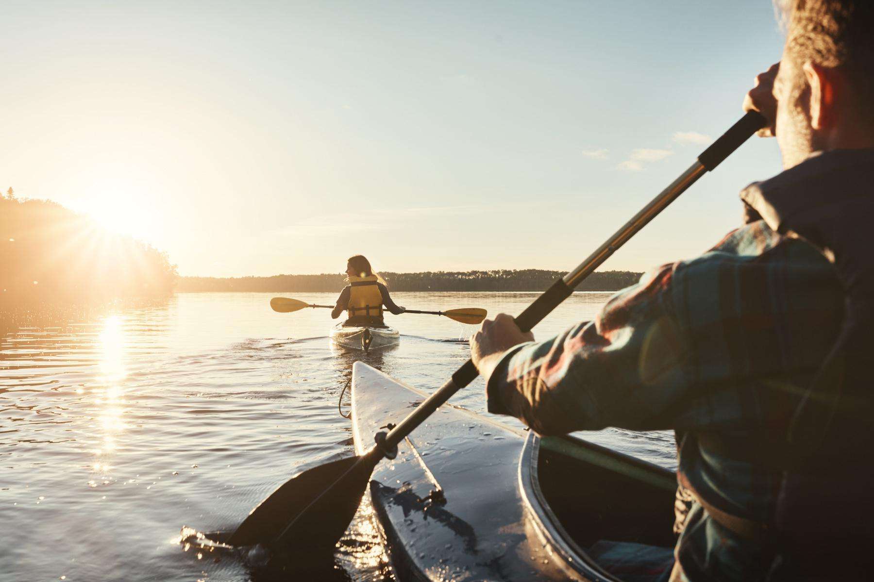 close-up of man and woman kayaking into sunset