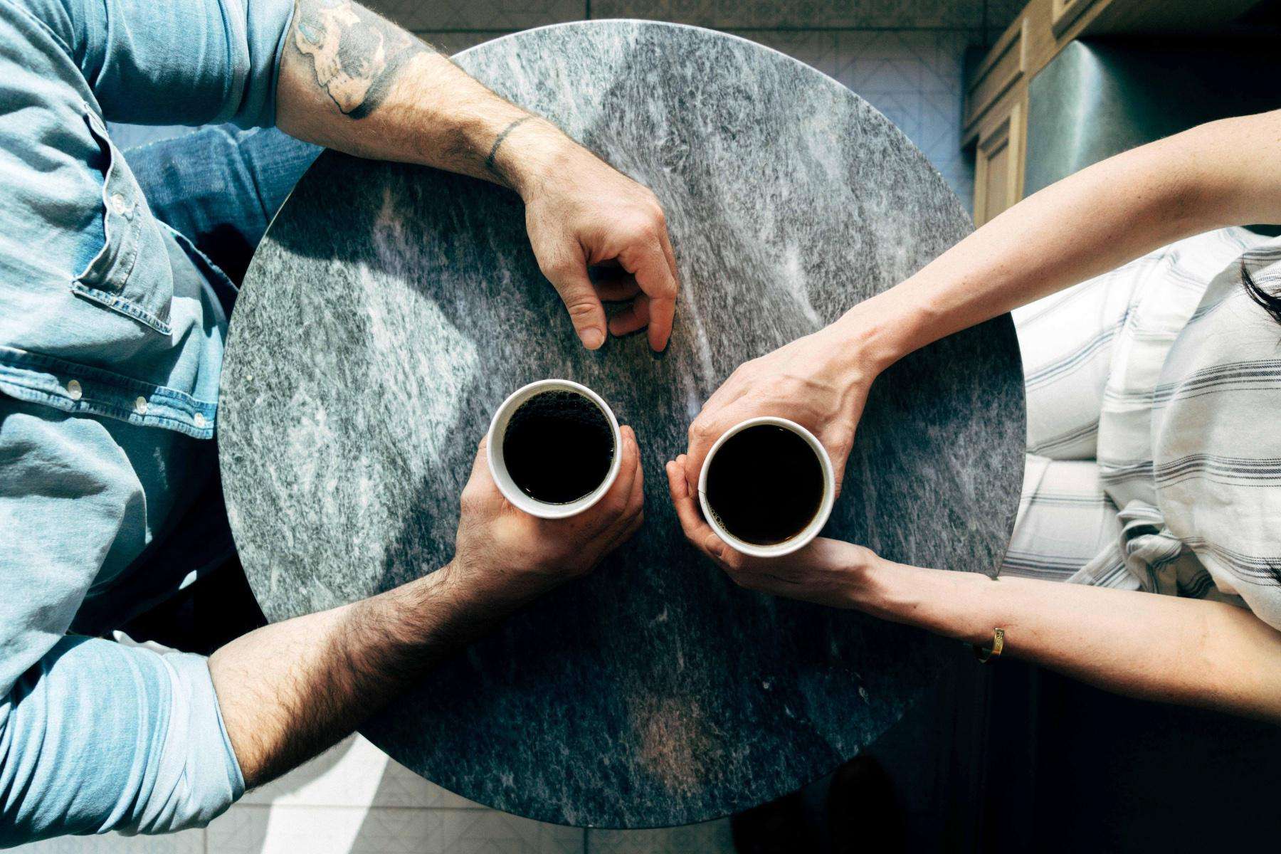 overhead view of two people with coffee cups at round table