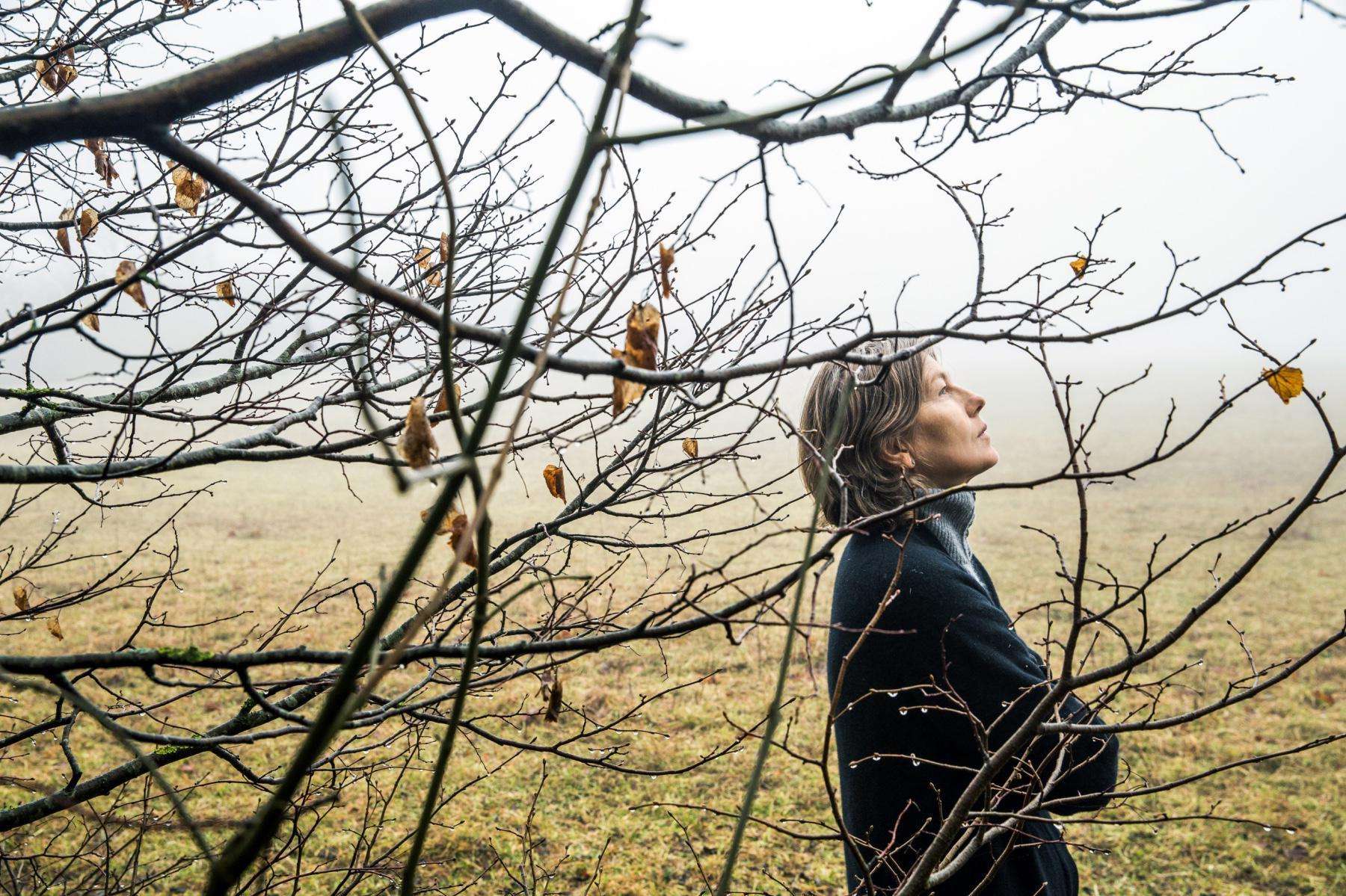 Woman standing next to a tree.