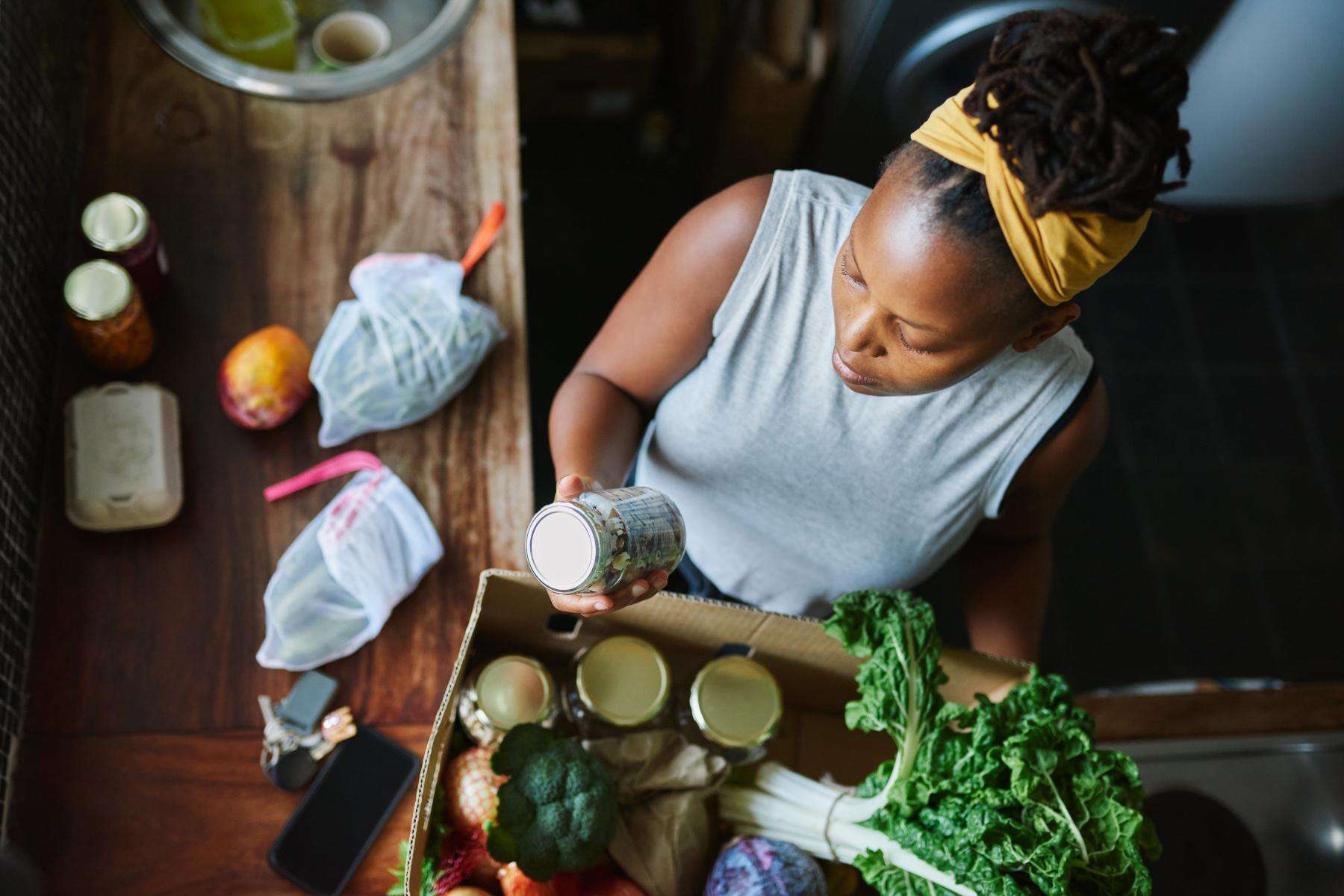 Overhead shot of woman reading food label on jar.