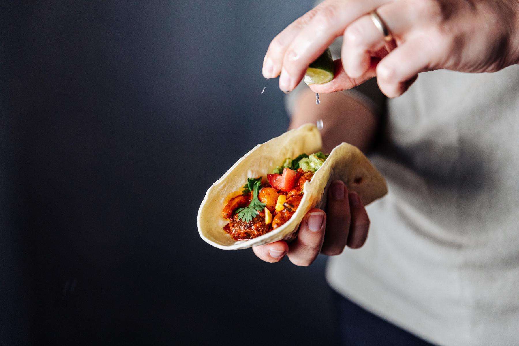 close-up of hand squeezing lime on a taco