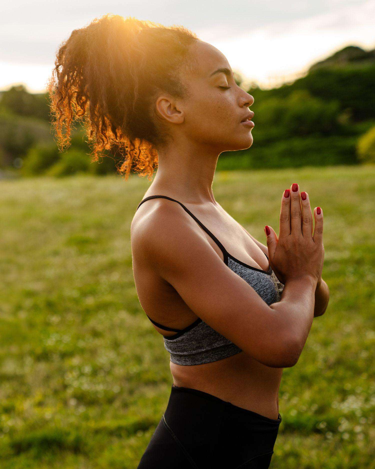 a woman meditating in a summer sunrise