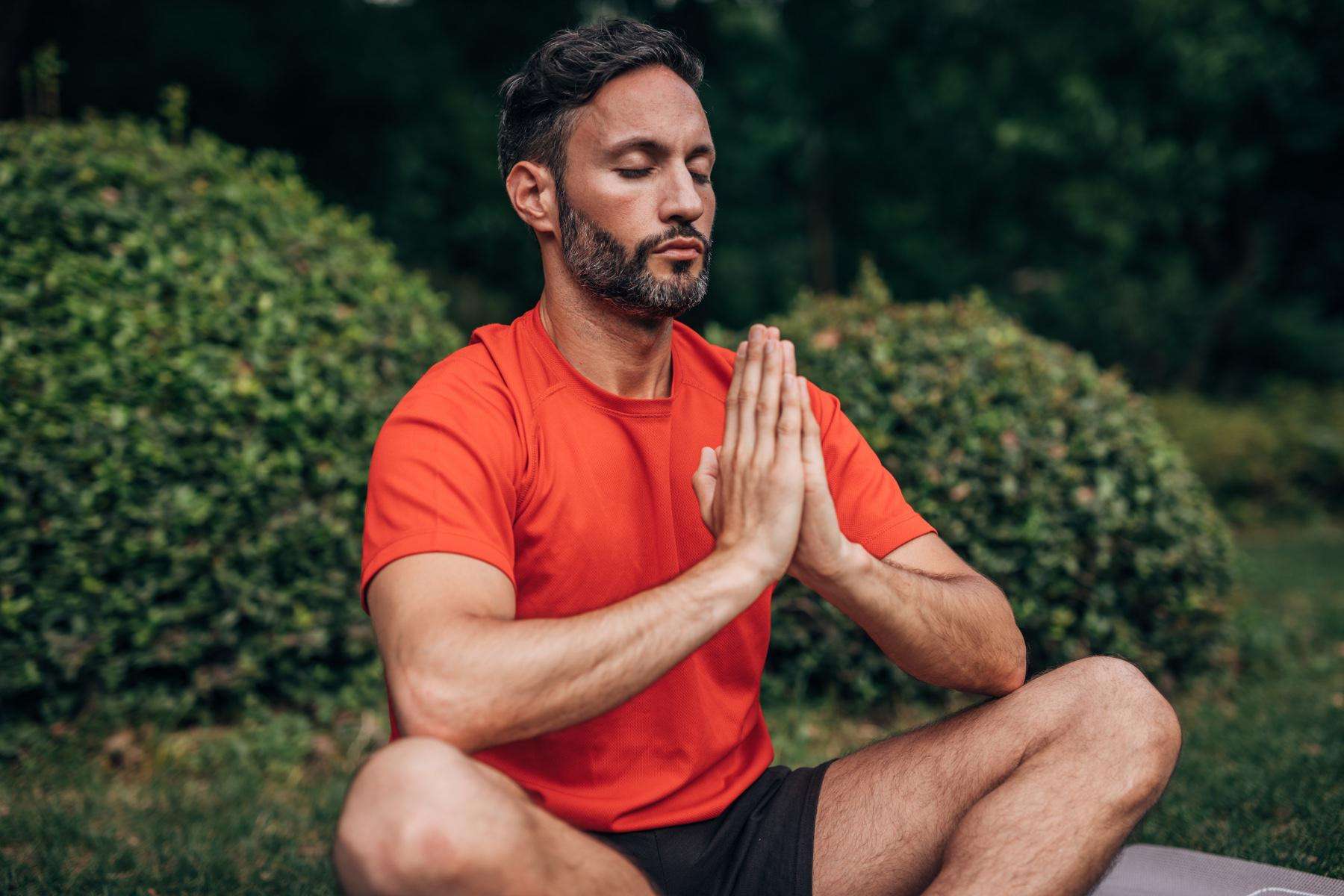 A man meditating in a park.