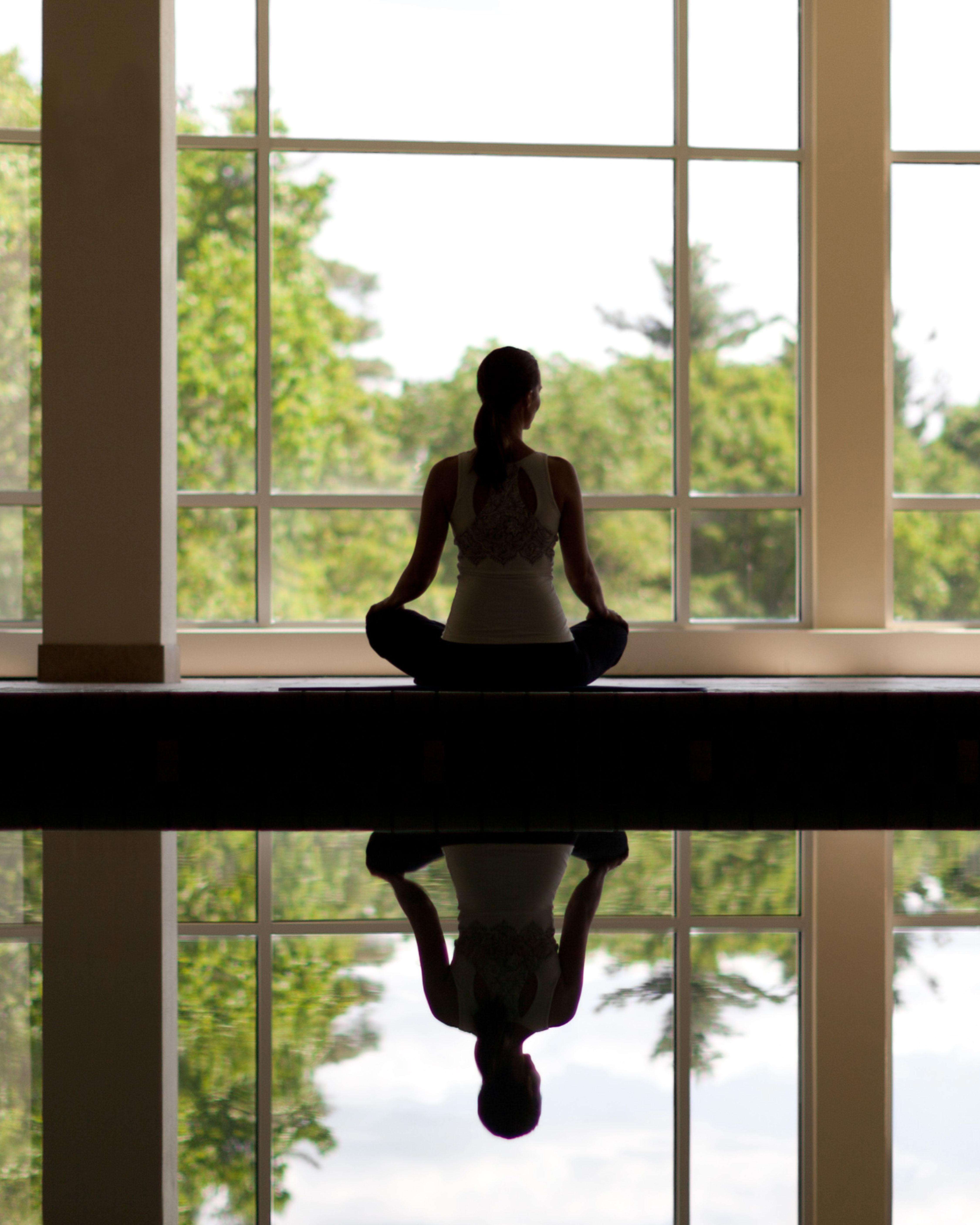 A woman sitting by an indoor swimming pool