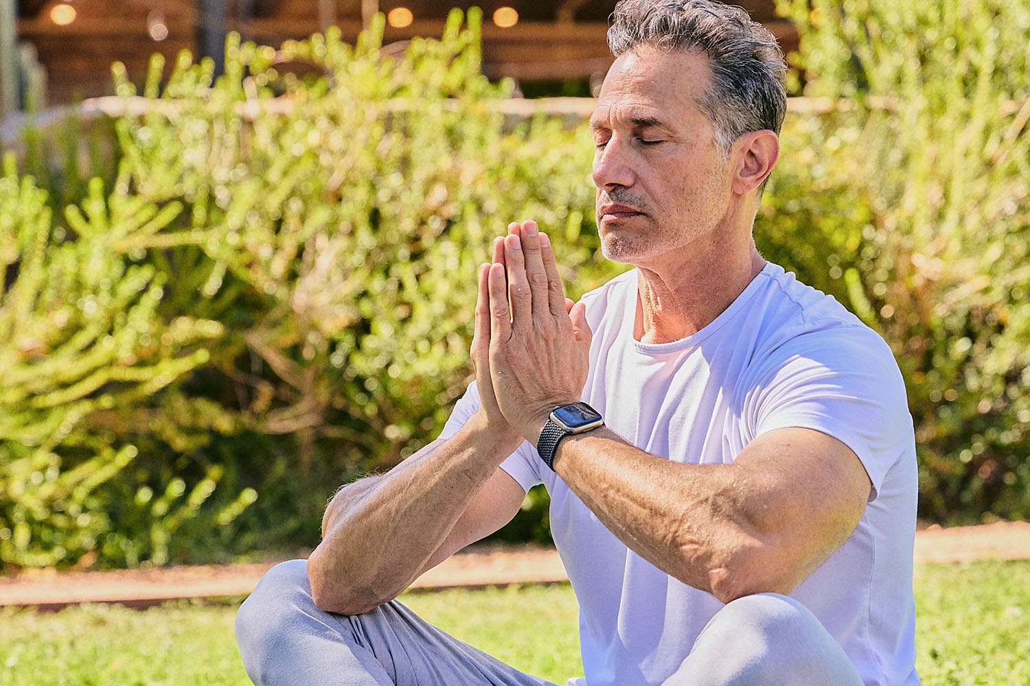 An older woman spreading her arms under a blue sky