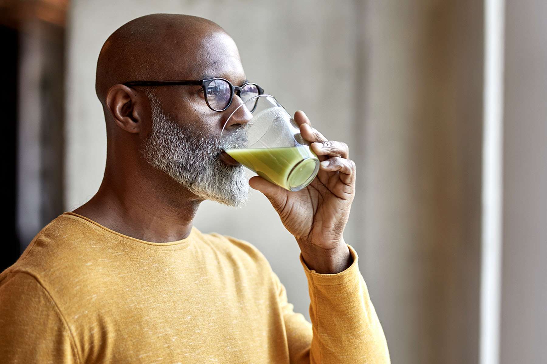A man drinking a green health smoothie