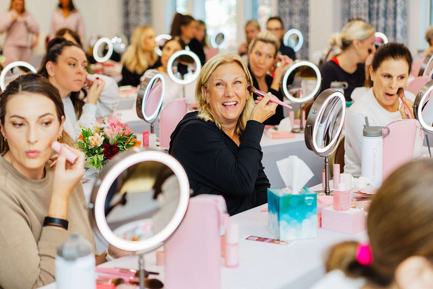 a group of women doing their makeup 