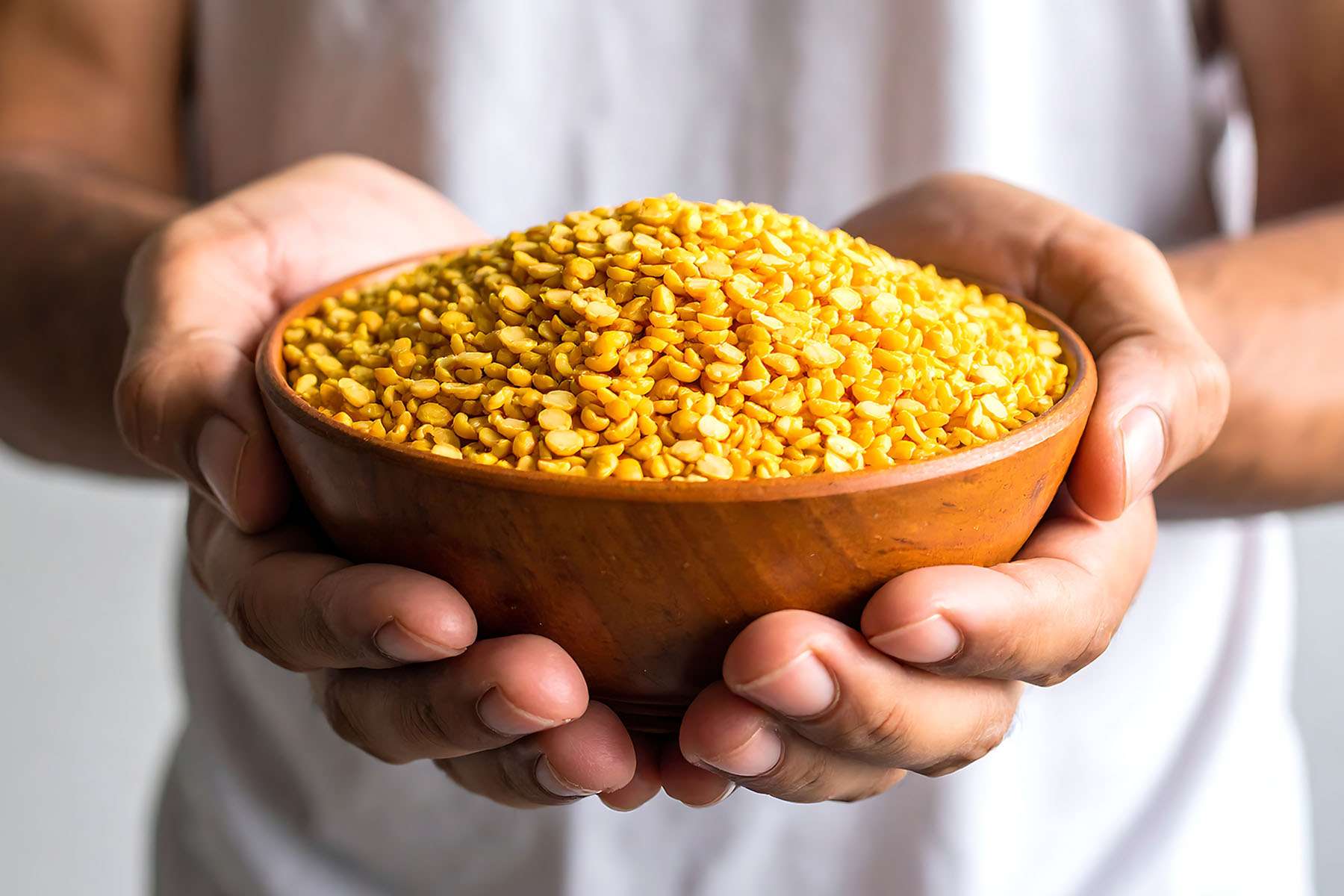 a person holding a bowl of yellow lentils