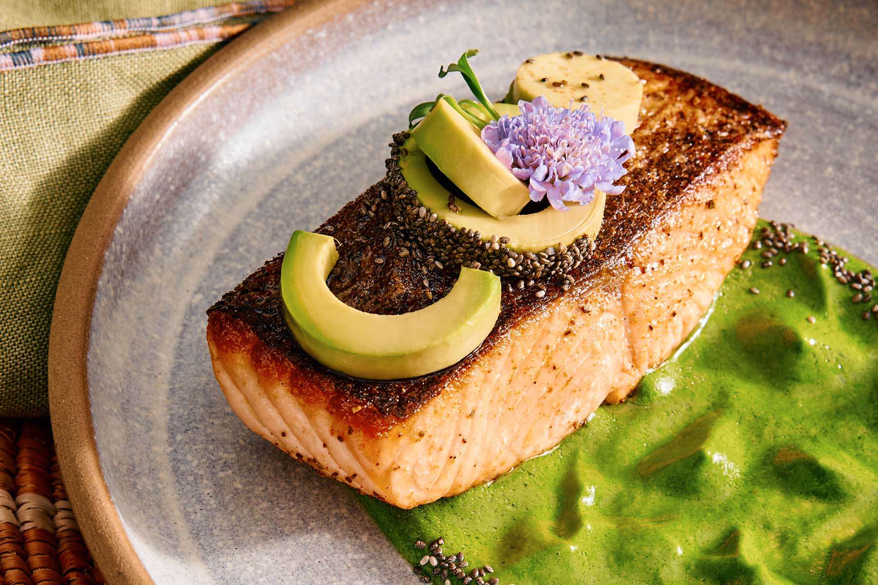 a plate of salmon on an herb dressing