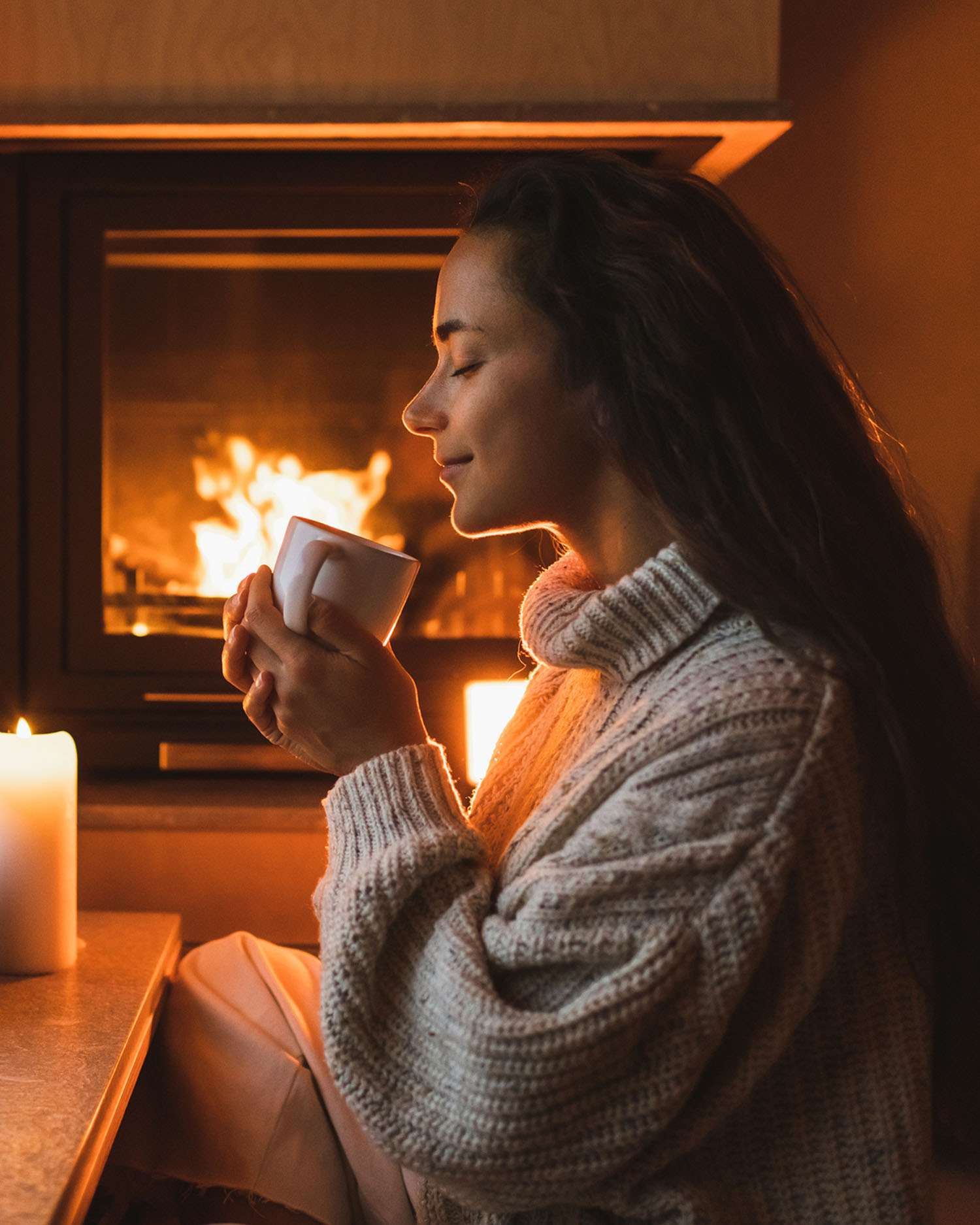 Woman Drinking a Hot Drink in Front of a Fire