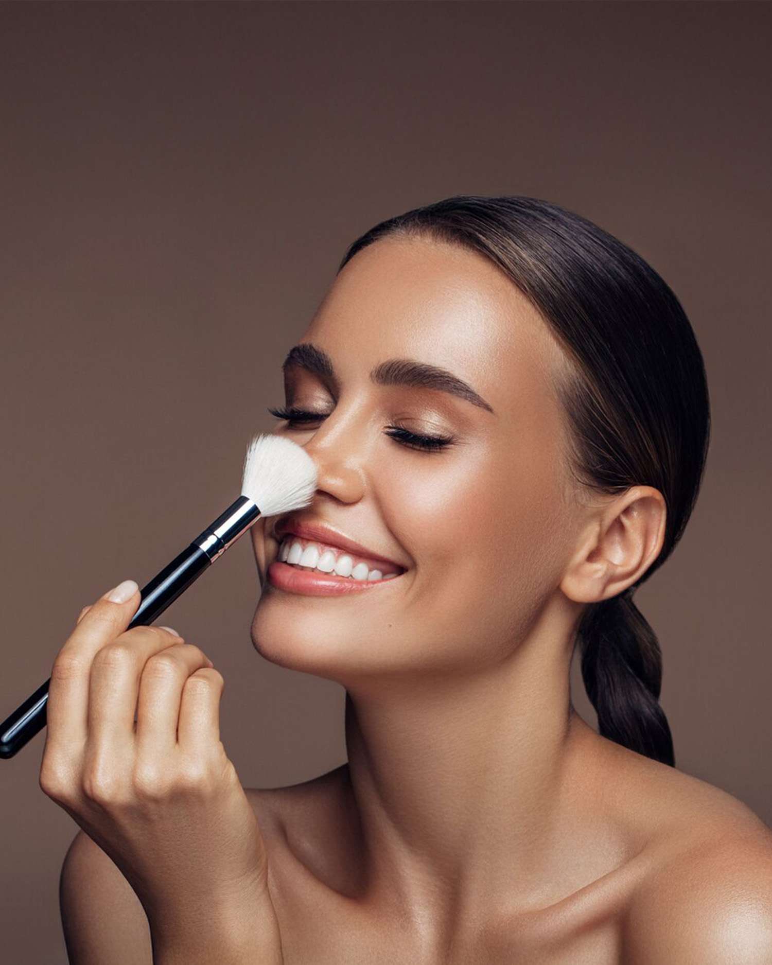 Woman Smiling with Make Up Brush on Her Face