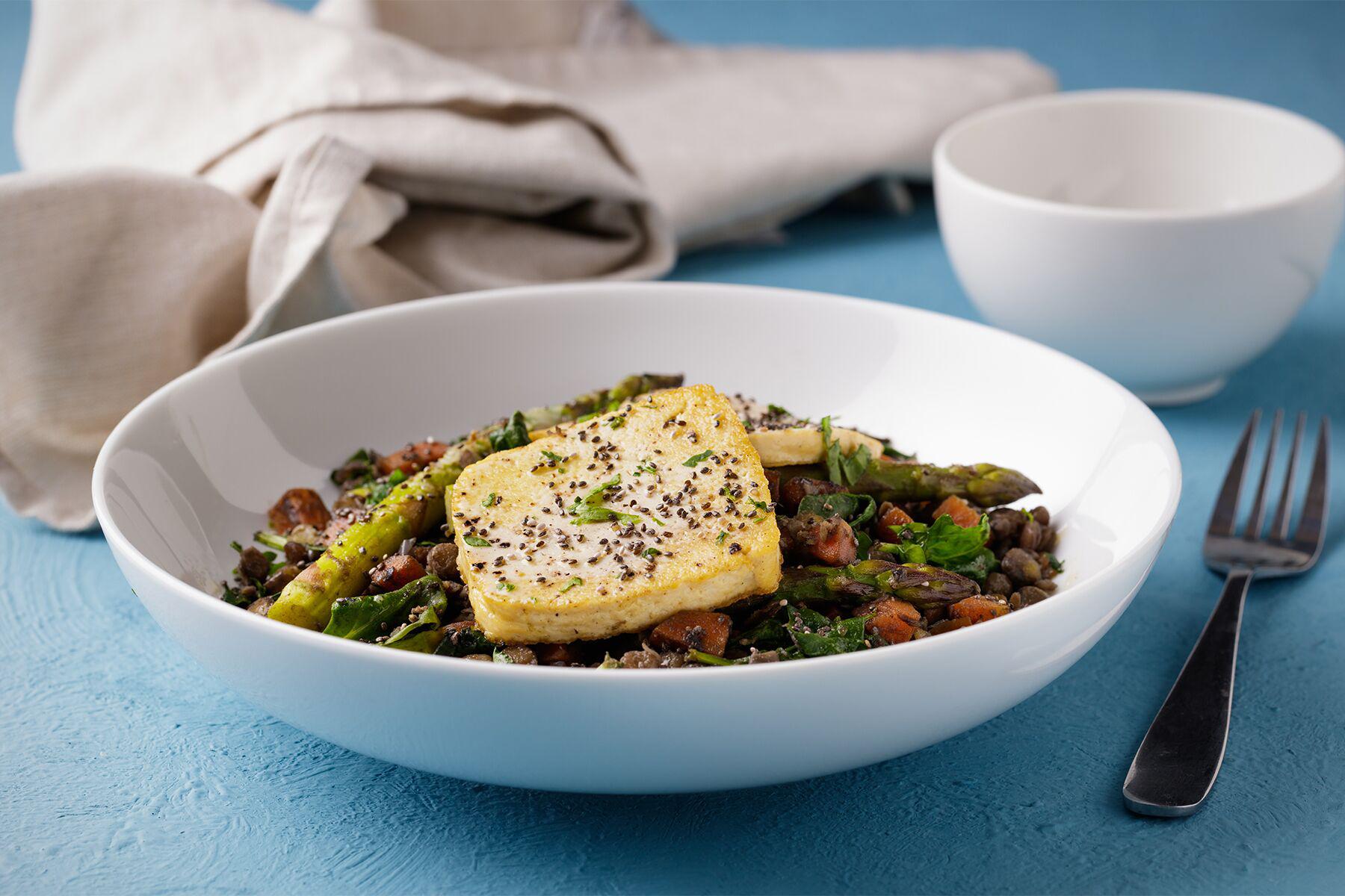 A bowl of Herbed Beluga Lentils with a slice of bread on top.