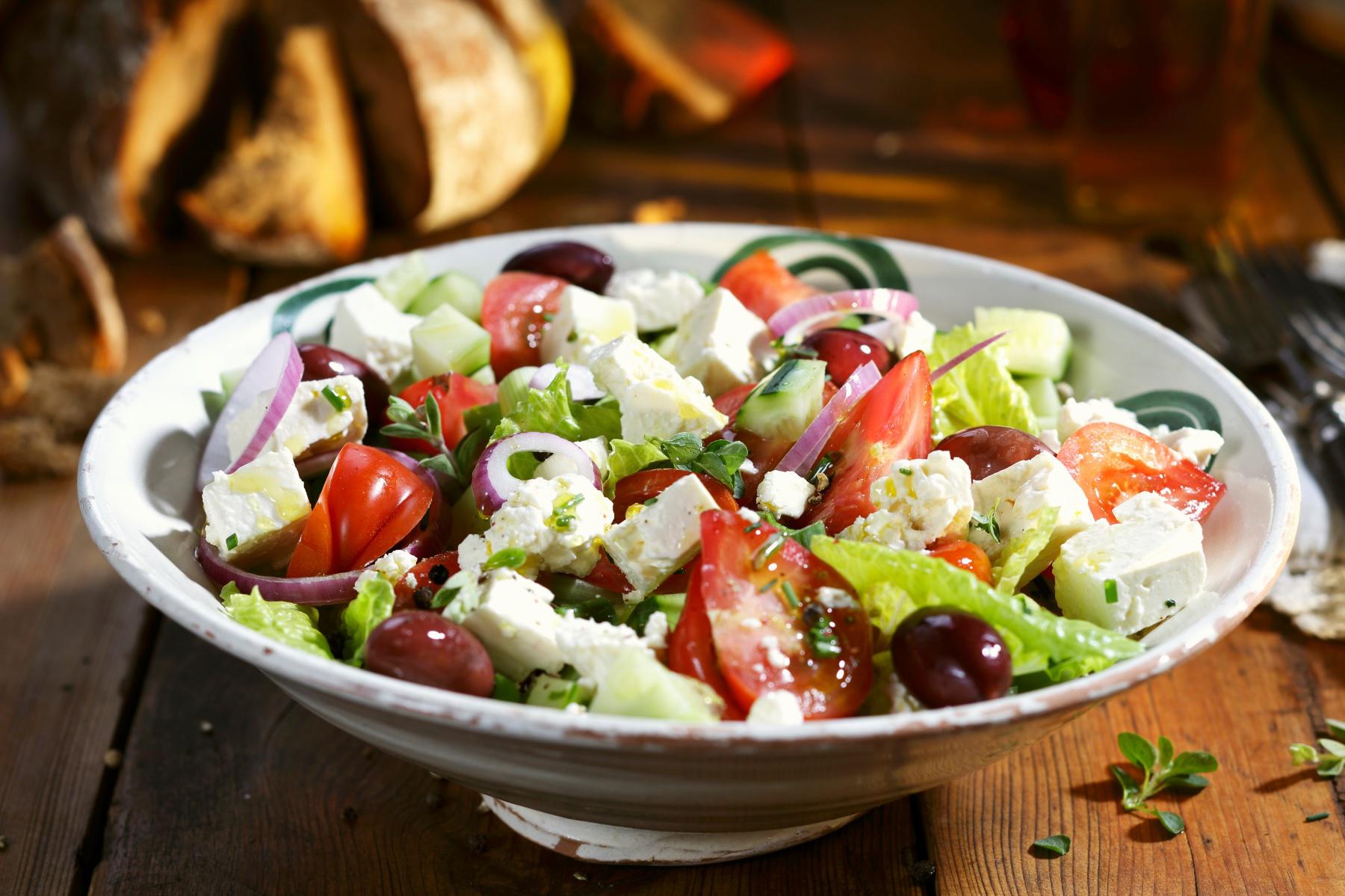 Bowl of greek salad with red wine vinaigrette drizzled on top.