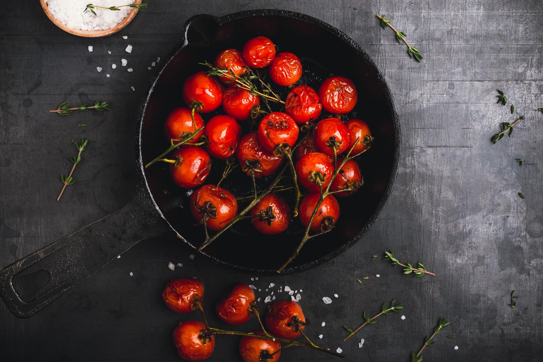 Cast iron pan filled with roasted tomatoes.