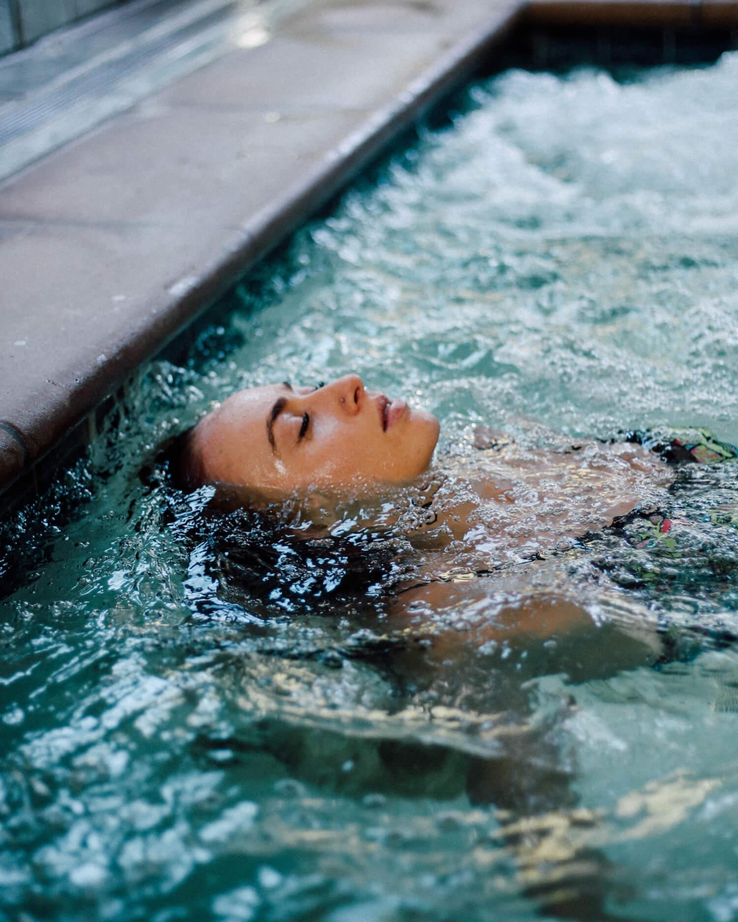 A woman smiling and splashing in the pool