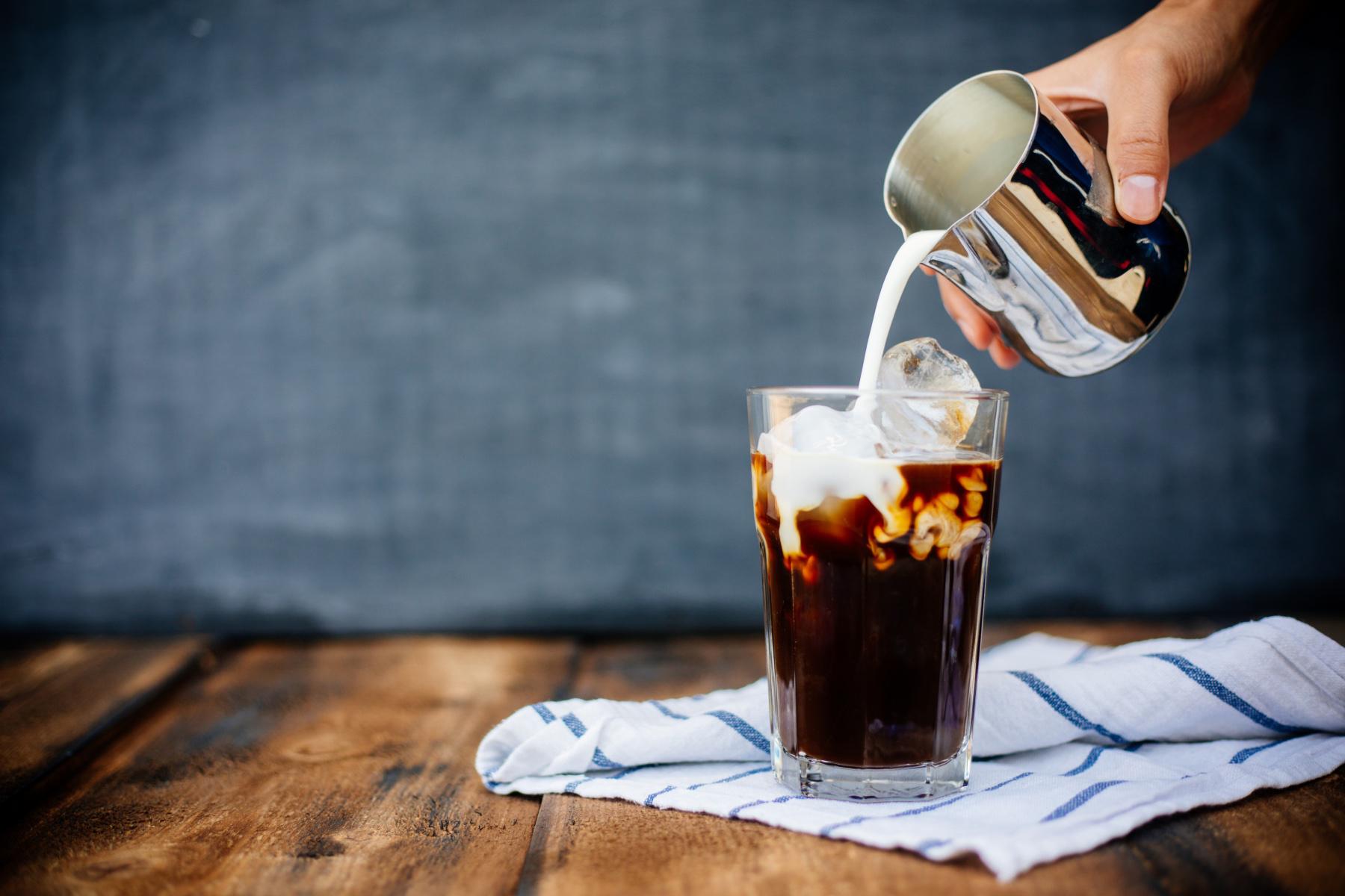 pouring milk into iced coffee