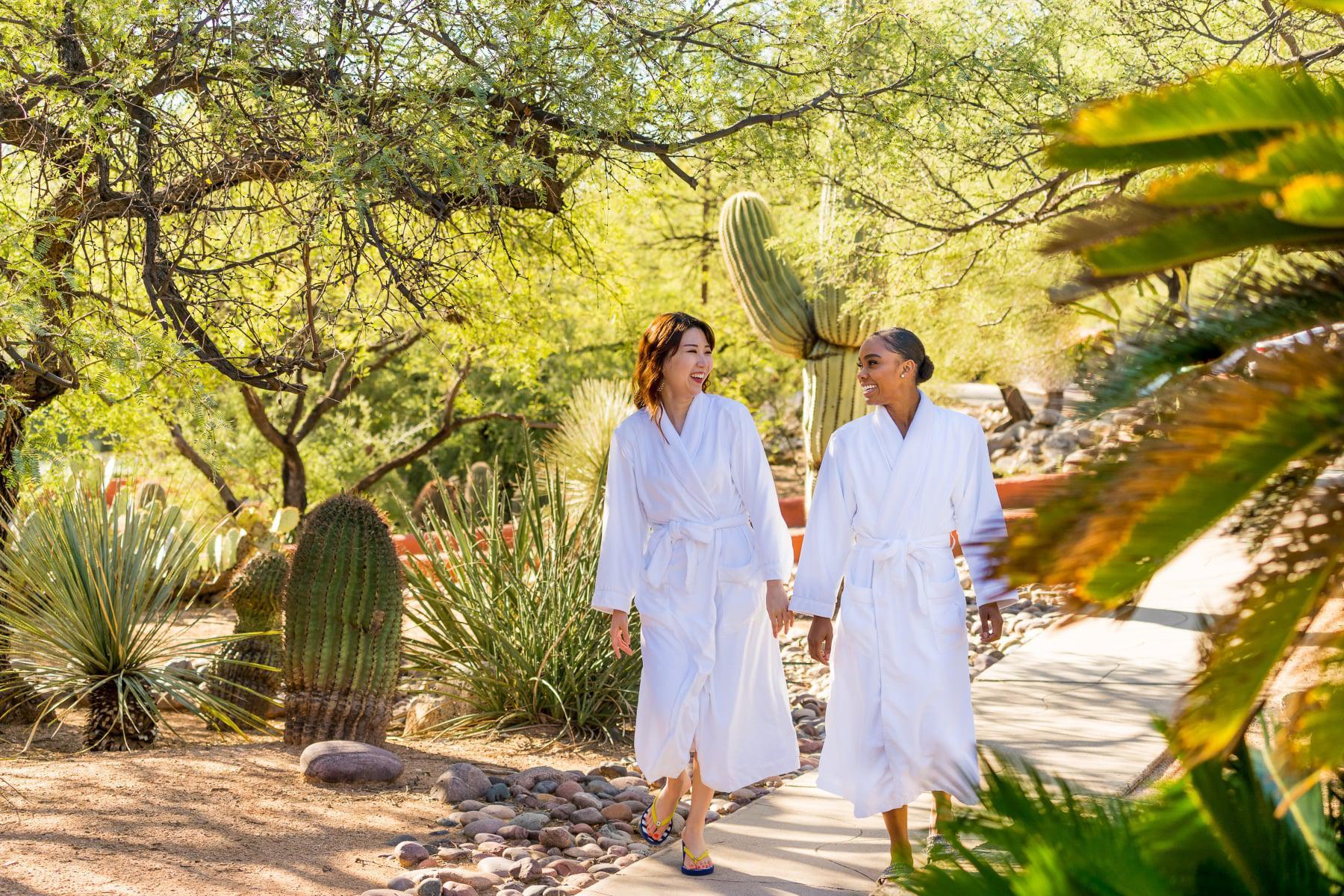 Two women in robes talking as they walk around the Canyon Ranch Tucson property.