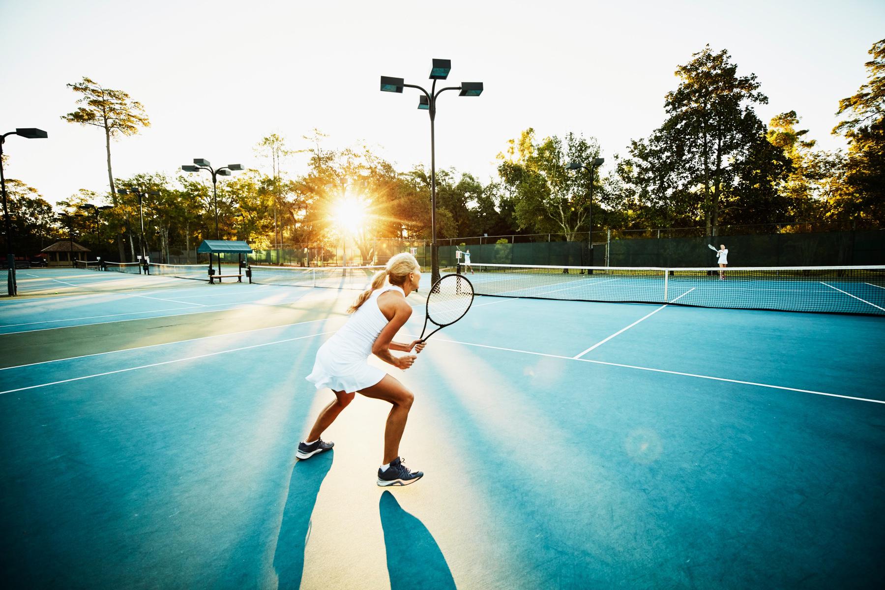 woman mid-tennis game out blue outdoor court