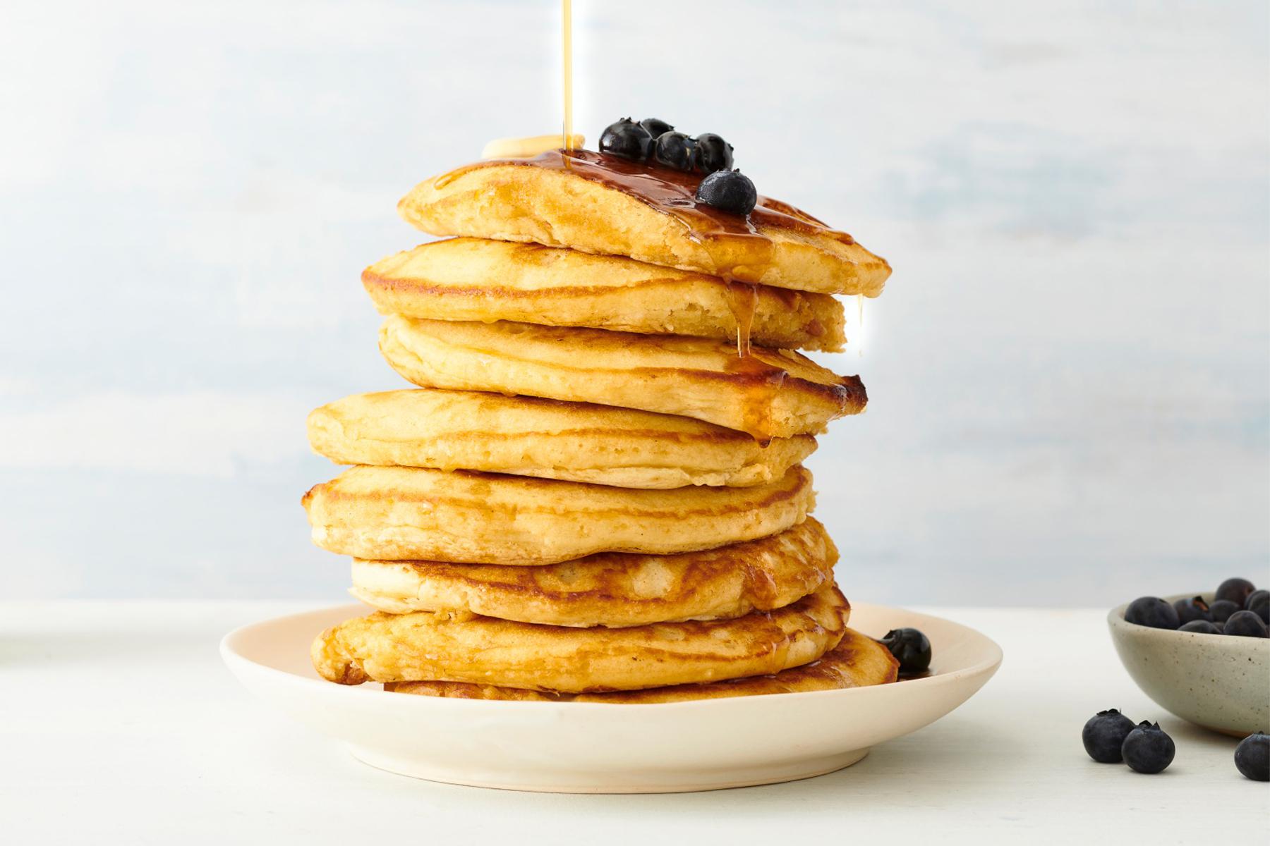Stack of whole-wheat pancakes with blueberries on top.