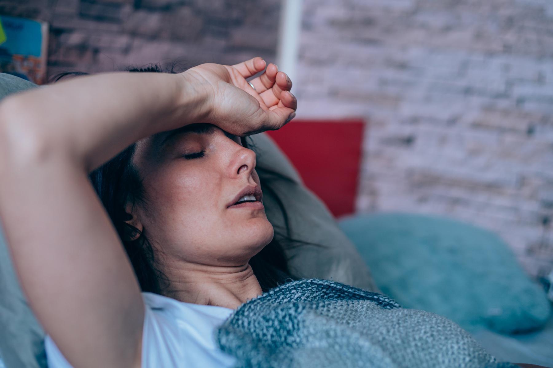 Woman having trouble sleeping close-up with arm on forehead.