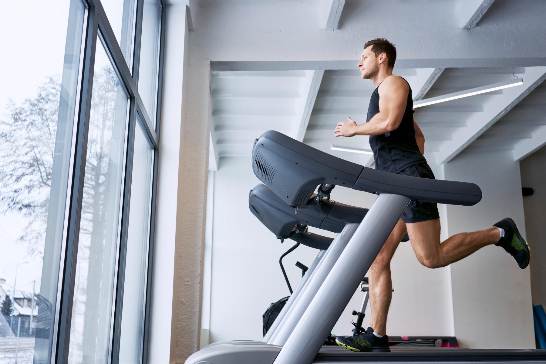 side view of man running on treadmill in gym