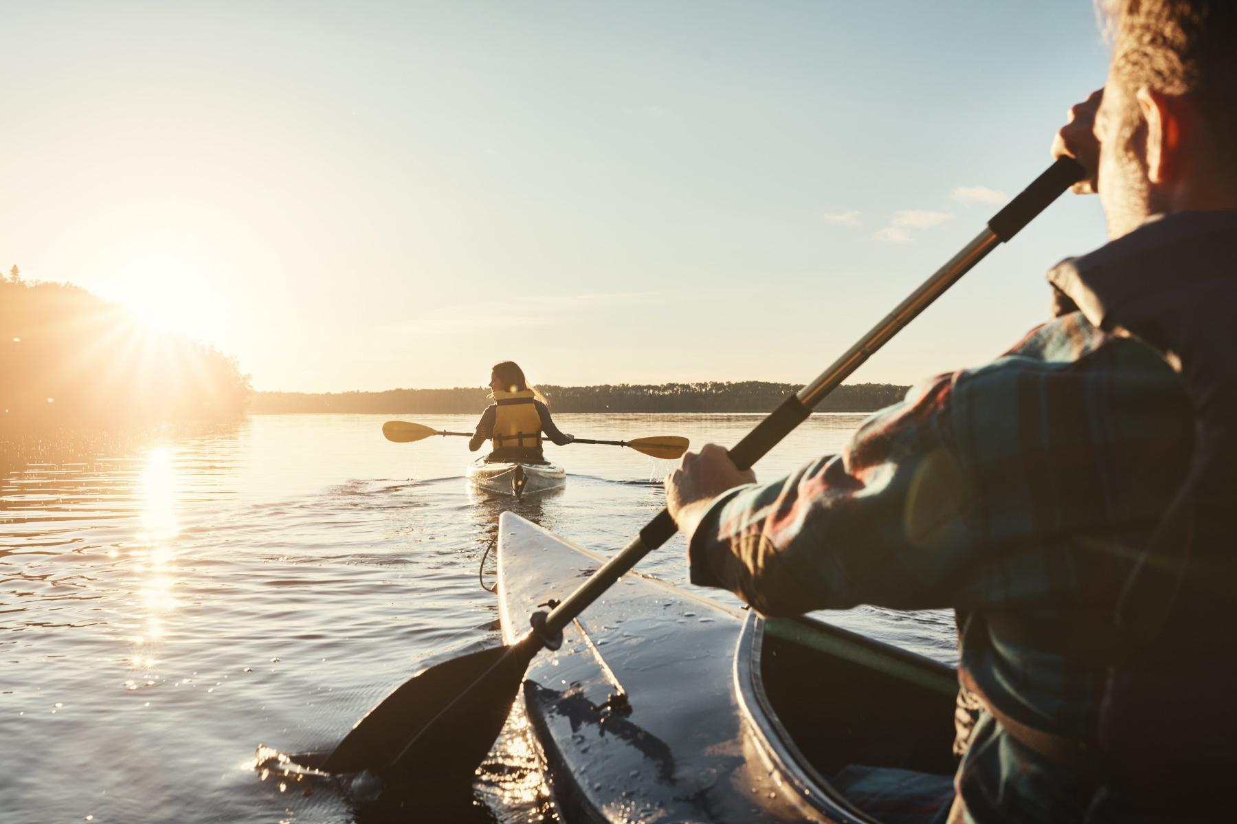 close-up of man and woman kayaking into sunset