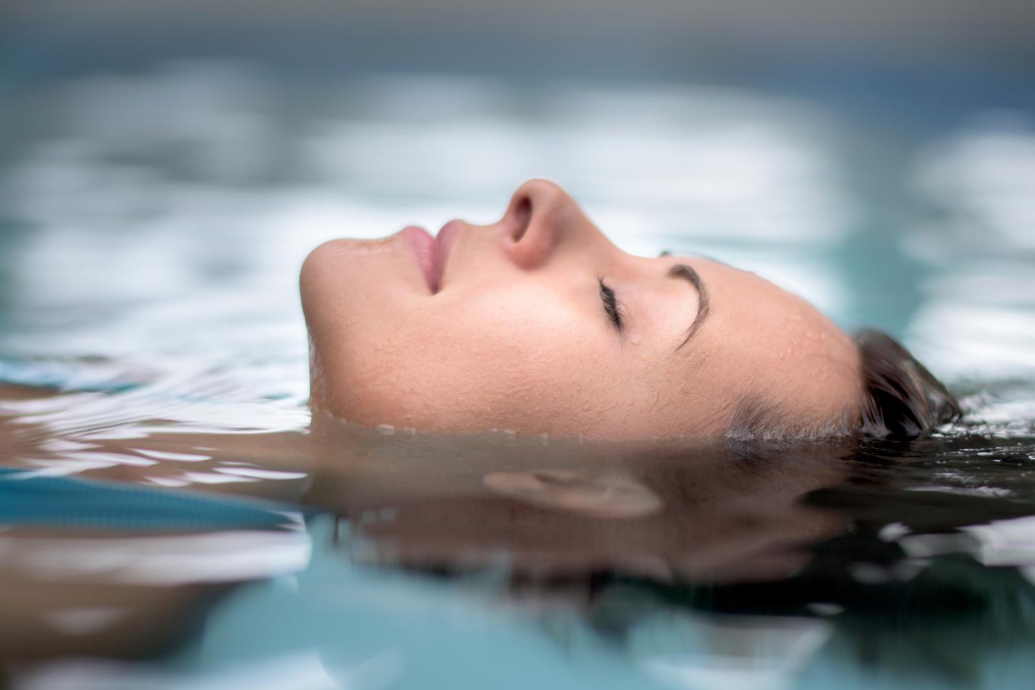 A woman smiling and splashing in the pool