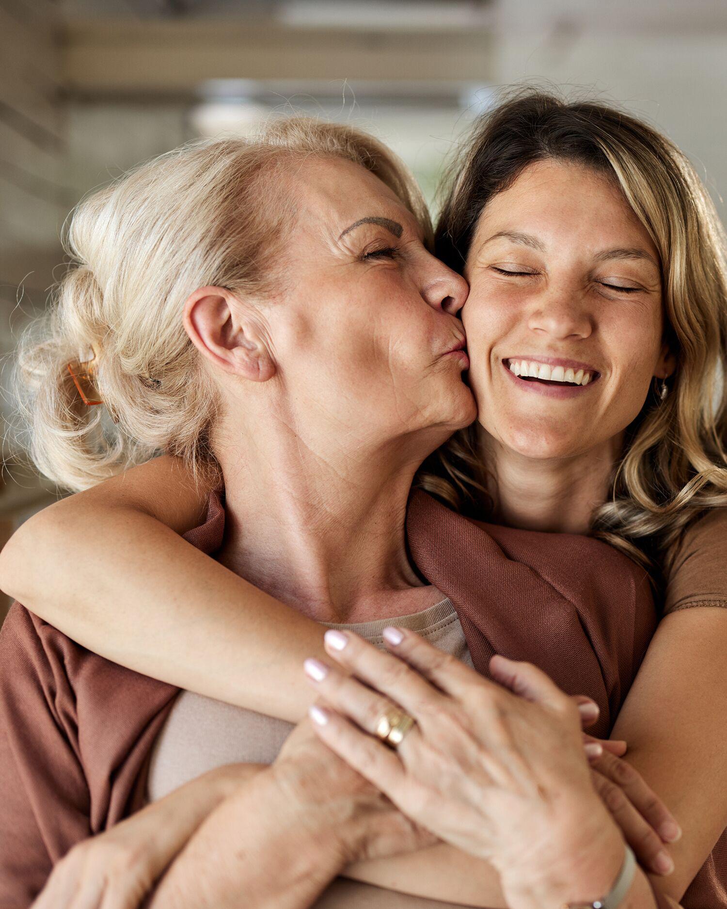 Daughter hugging mother and smiling.