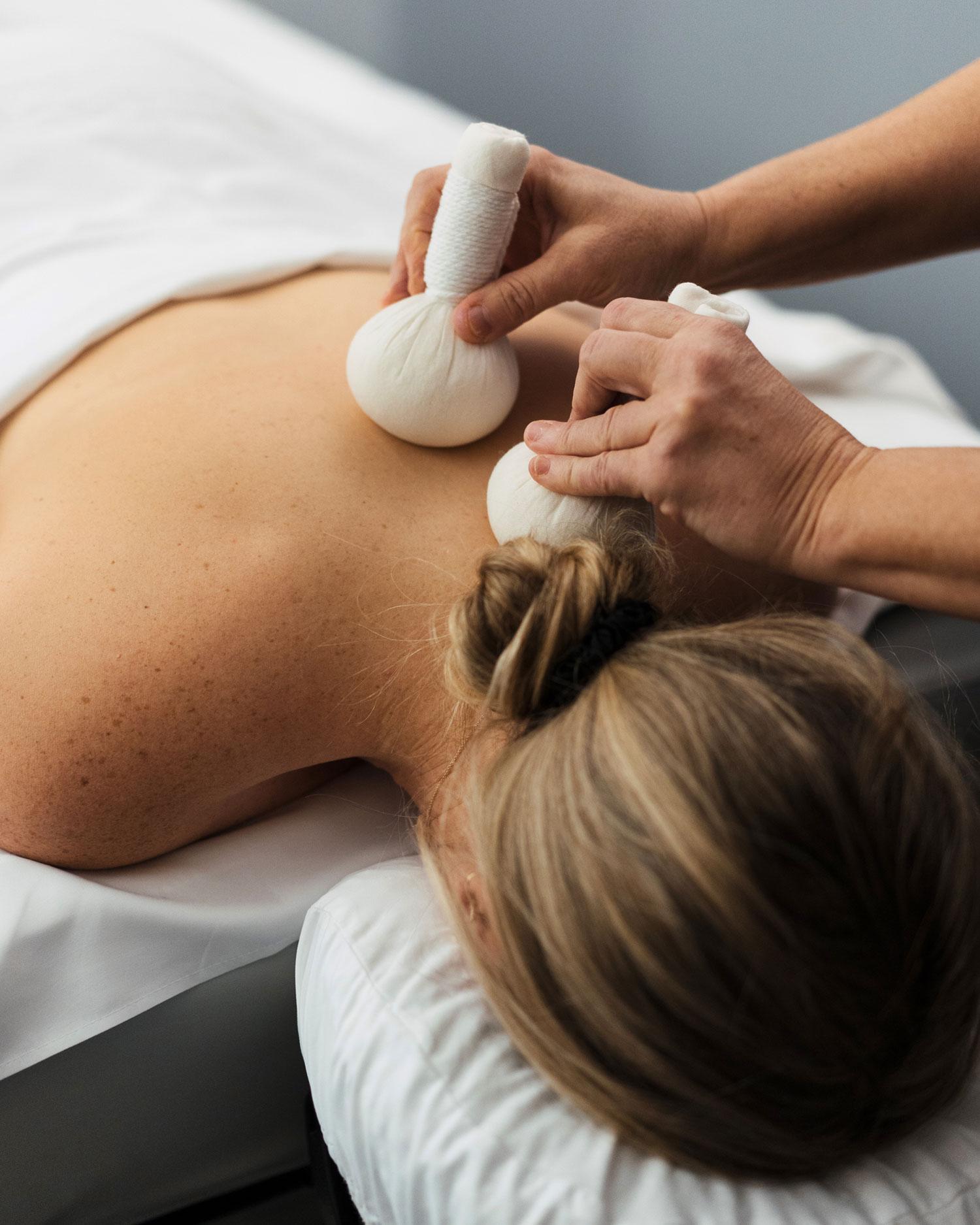 Close-up image of a woman receiving a spa body treatment with two poultices on her back at Canyon Ranch.