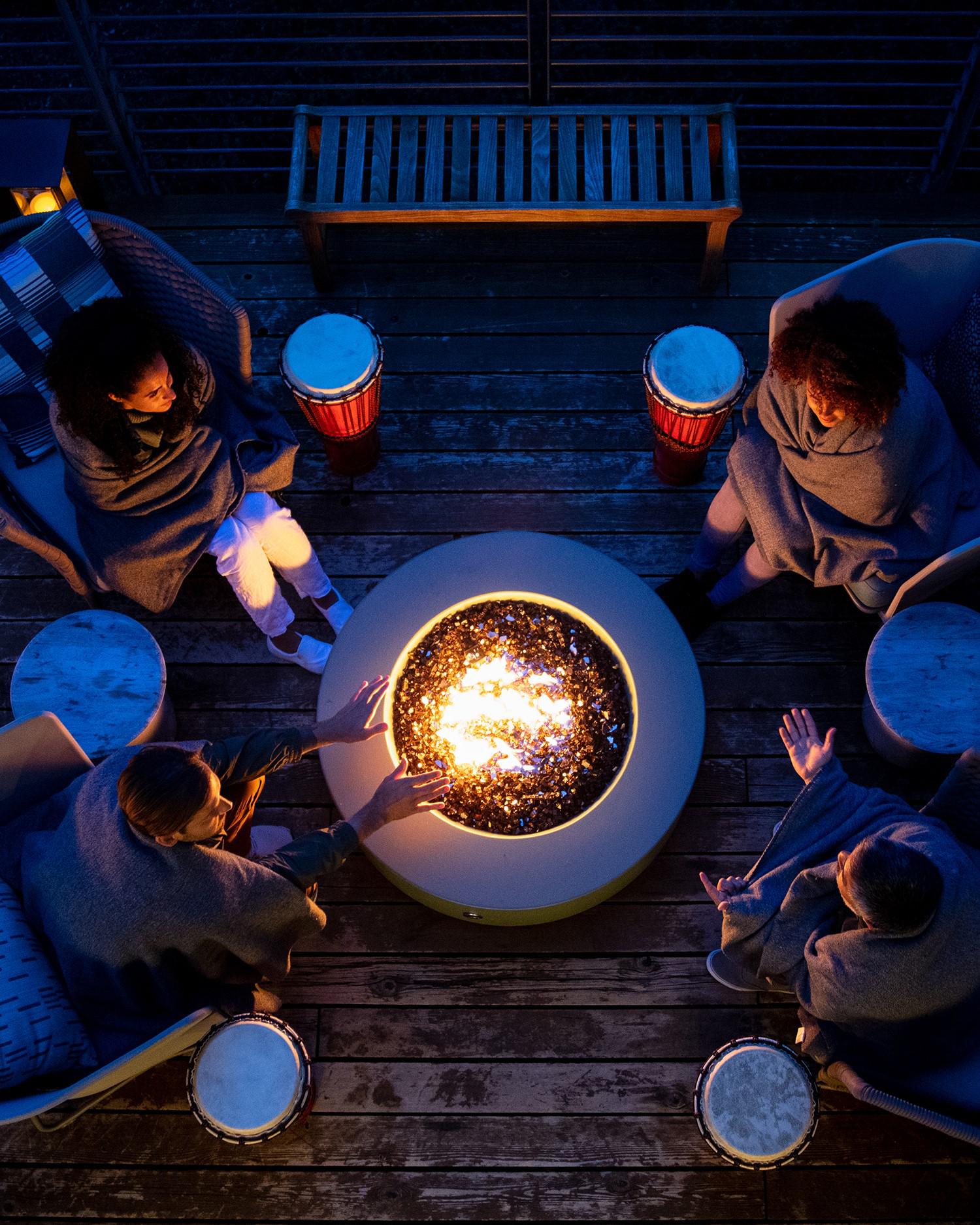 group sitting around fire pit on deck chatting and drinking wine