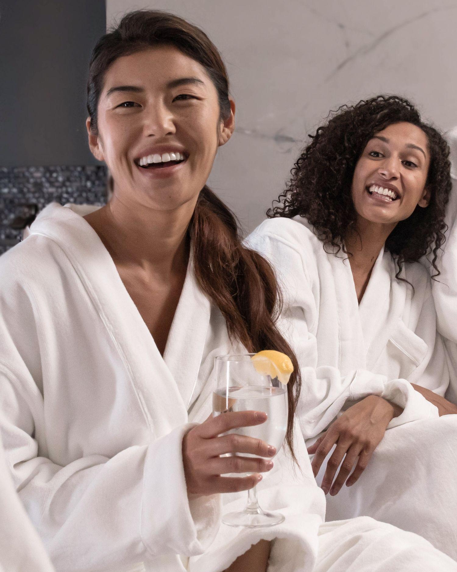 Two girlfriends in robes a the spa laughing with each other