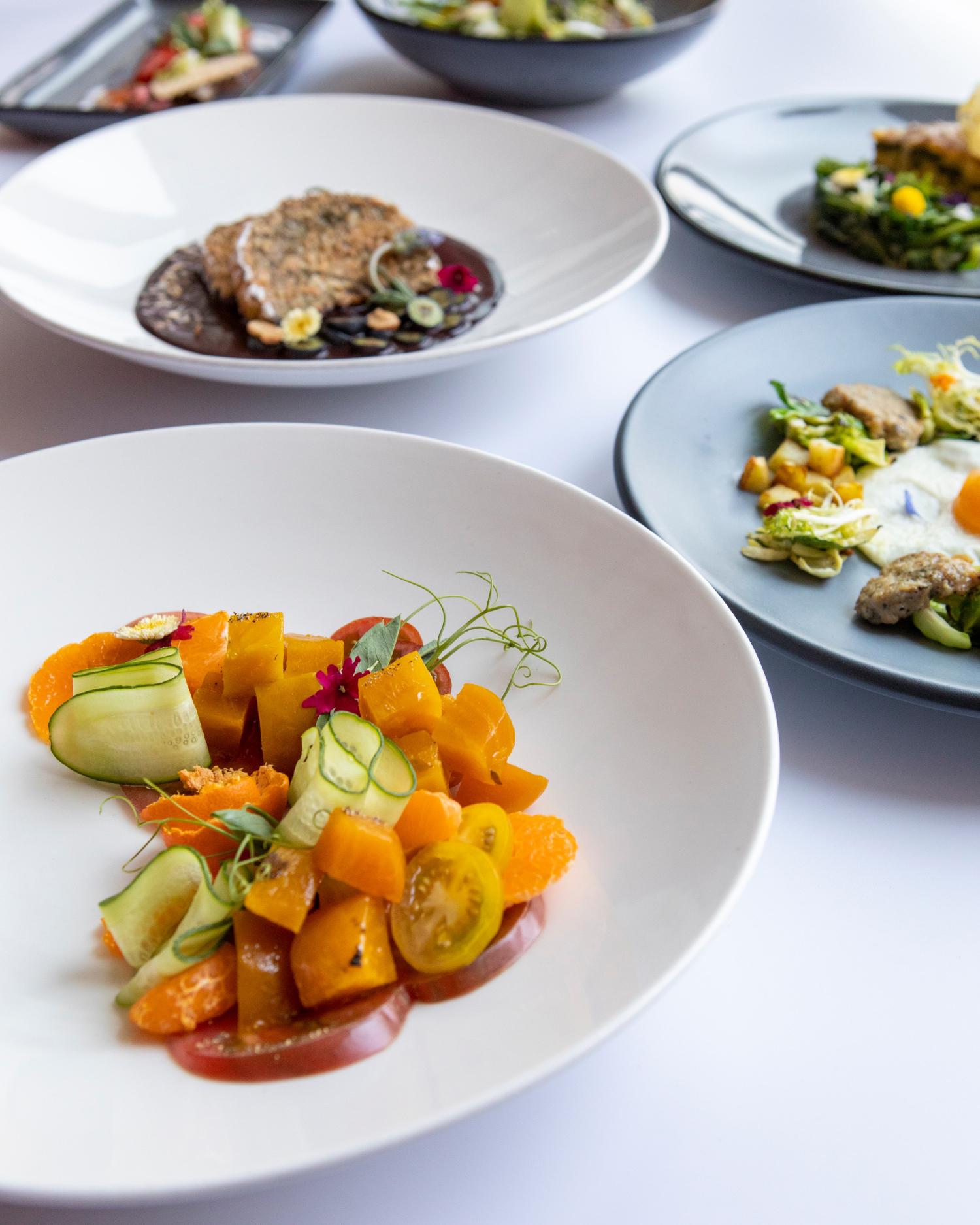 Various entrees from a plate of tomatoes and cucumbers to steak.