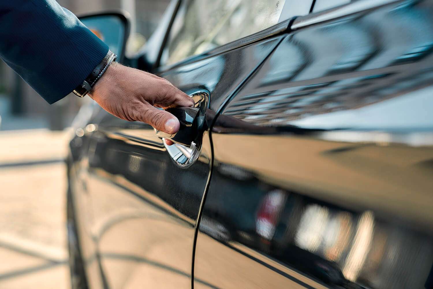 A man opening a black towncar door
